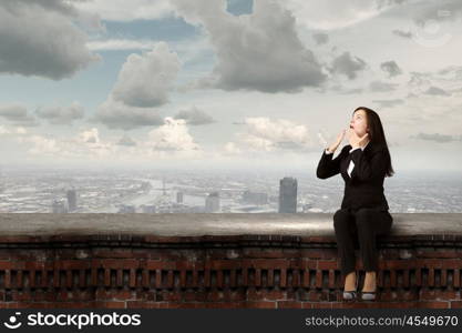 Surprised businesswoman. Young emotional businesswoman sitting on building top