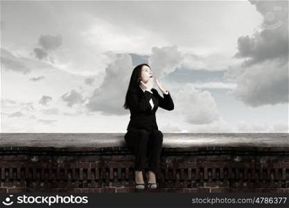 Surprised businesswoman. Young emotional businesswoman sitting on building top