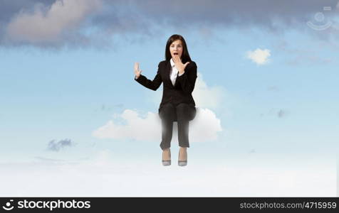 Surprised businesswoman. Young emotional businesswoman sitting on cloud above city