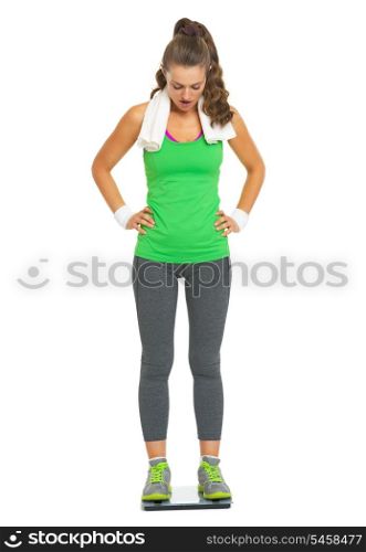 Surprised fitness young woman standing on scales