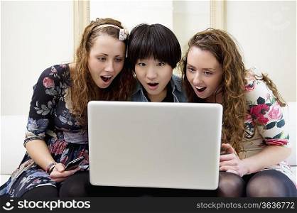 Surprised friends looking at something in laptop