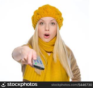 Surprised girl in autumn clothes using tv remote control