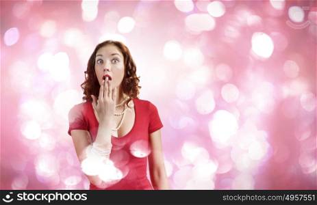 Surprised girl. Young pretty girl in red dress against bokeh background