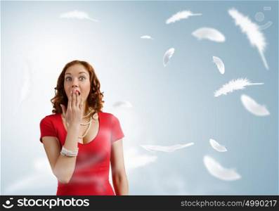 Surprised girl. Young pretty girl in red dress and feathers flying in air
