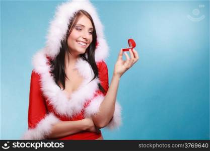 Surprised happy girl young woman wearing santa claus costume opening present red heart shaped gift box with engagement ring on blue background. Christmas time gifts.