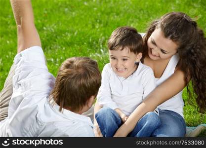 Surprised kid on hands at parents on a lawn
