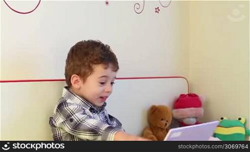 Surprised little boy watching laptop at home