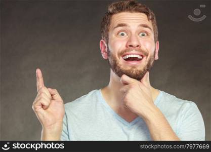 Surprised man pointing at empty blank copy space.. Portrait of surprised scared handsome man pointing at empty blank copy space. Young guy in studio on black. Advertisement.