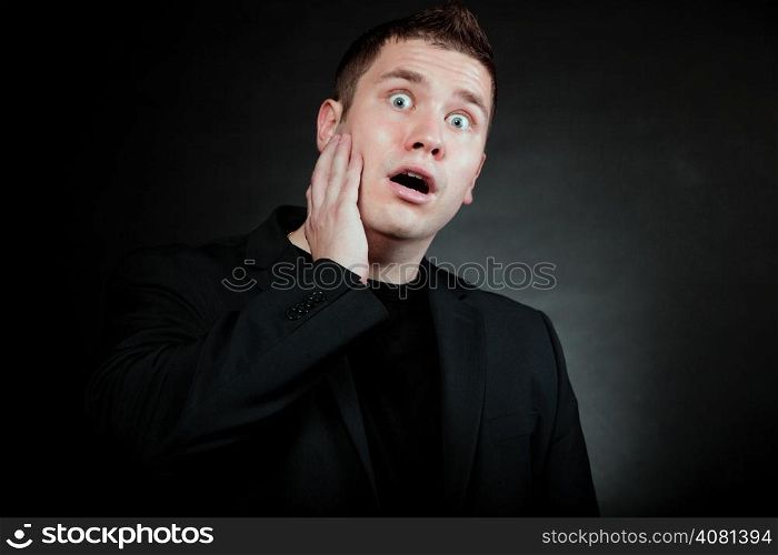 surprised shocked man face hand over mouth wide eyed black background