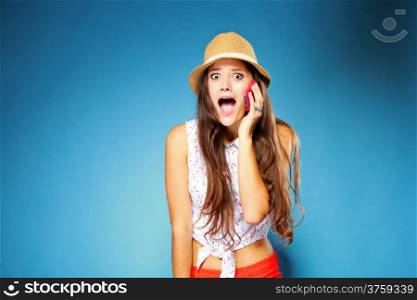 Surprised shocked summer girl talking on mobile phone, blue background