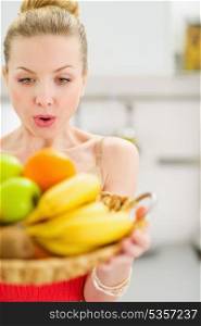 Surprised teenage girl holding plate of fruits