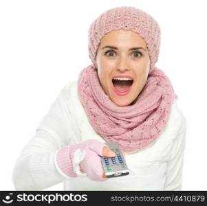 Surprised woman in knit winter clothing using TV remote control