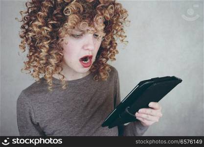 surprised woman looking her bills in an ipad