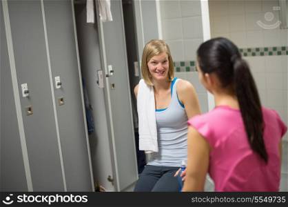 Surprised woman talking with friend in changing room at healthclub