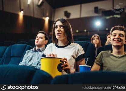 Surprised woman with popcorn watching film in cinema. Showtime, movie. Surprised woman watching film in cinema