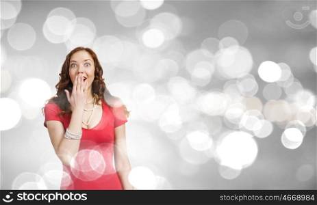 Surprised woman. Young pretty woman in red dress against bokeh background