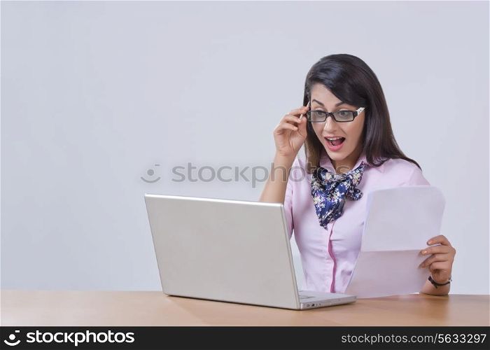 Surprised young businesswoman using laptop at office desk