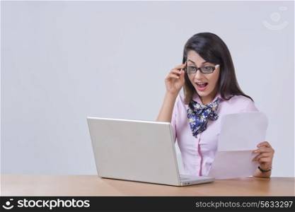 Surprised young businesswoman using laptop at office desk