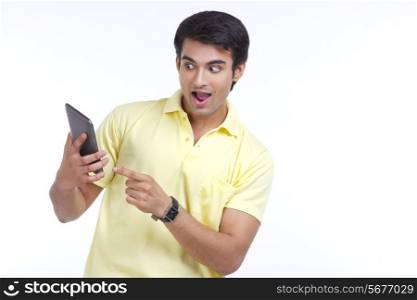 Surprised young man holding digital tablet isolated over white background