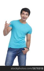 Surprised young man pointing over white background