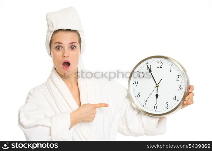 Surprised young woman in bathrobe pointing on clock