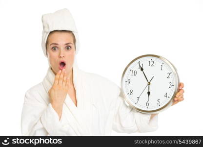 Surprised young woman in bathrobe with clock