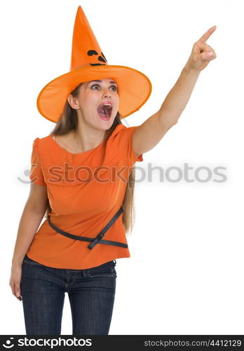 Surprised young woman in Halloween hat pointing on copy space