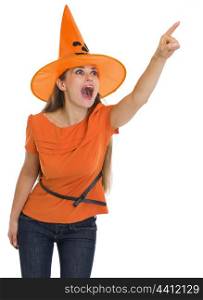 Surprised young woman in Halloween hat pointing on copy space