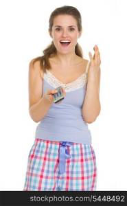 Surprised young woman in pajamas with TV remote control