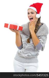 Surprised young woman in sweater and christmas hat looking on christmas present box