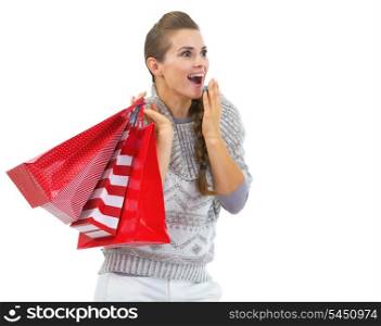 Surprised young woman in sweater with christmas shopping bags looking on copy space