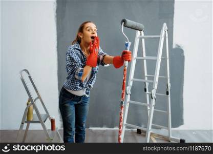 Surprised young woman makes home repair, happy female person doing appartment renovation, room decoration renovating. Surprised young woman makes home repair