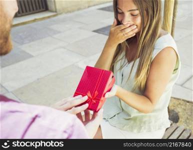 surprised young woman receiving gift from her boyfriend