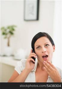 Surprised young woman speaking mobile phone