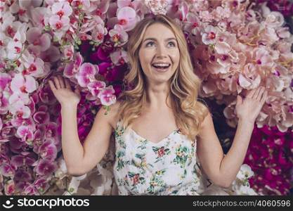 surprised young woman standing front pink orchid looking up