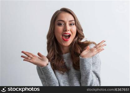 Surprised young woman. Surprised young woman in casual gray sweater on gray background