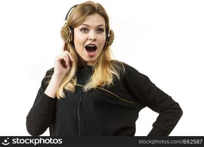 Surprised young woman wearing grunge headphones with spikes being amazed or suprised with what she is listening.. Suprised woman wearing headphones