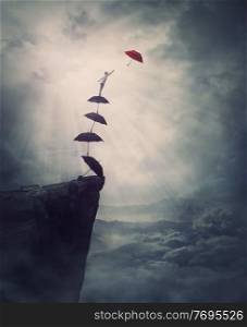 Surreal adventure, epic scene with a determined man climbing an improvised stairway of umbrellas, decided to reach a different one. Purposefulness and risk concept, on edge of a cliff, fighting fears