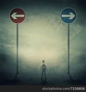 Surrealistic image as a man, with a bag in his back, stand in a foggy street in front of two huge road signs that show the left and right directions. Strategic journey, way of life and intuition concept.