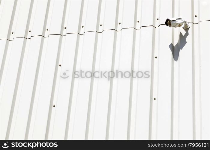 surveillance camera on wall of white industrial metal building