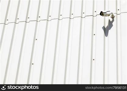 surveillance camera on wall of white industrial metal building