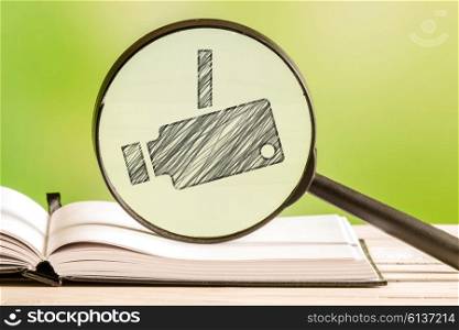 Surveillance investigation with a pencil drawing of a surveillance camera in a magnifying glass
