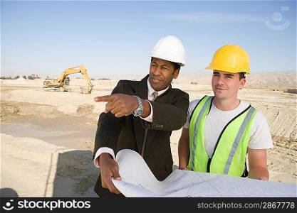Surveyor and construction worker holding blueprint