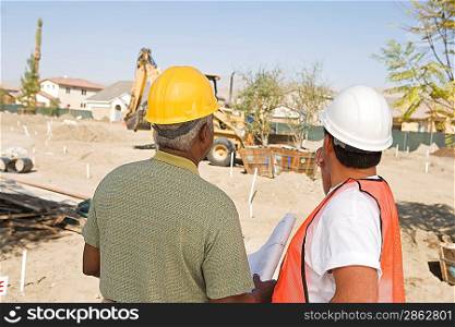 Surveyor and contraction worker at construction site, back view