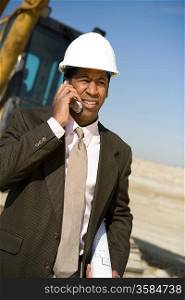 Surveyor using mobile phone on construction site
