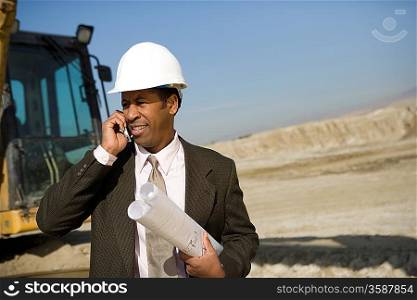 Surveyor using mobile phone on construction site