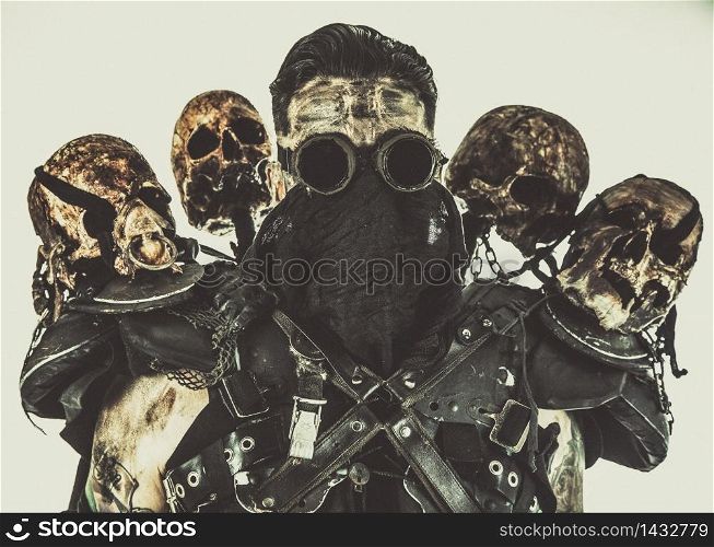 Survived in nuclear disaster mutant bandit or underground human creature, wearing rags and human skulls on shoulders. Post apocalyptic survivor with skulls