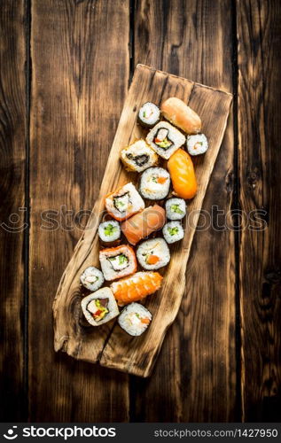 Sushi and rolls on the Board. On wooden background.. Sushi and rolls on the Board.