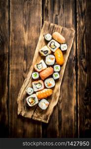 Sushi and rolls on the Board. On wooden background.. Sushi and rolls on the Board.