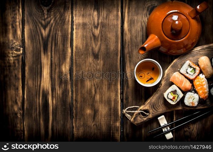 Sushi and rolls with herbal tea. On a wooden table.. Sushi and rolls with herbal tea.